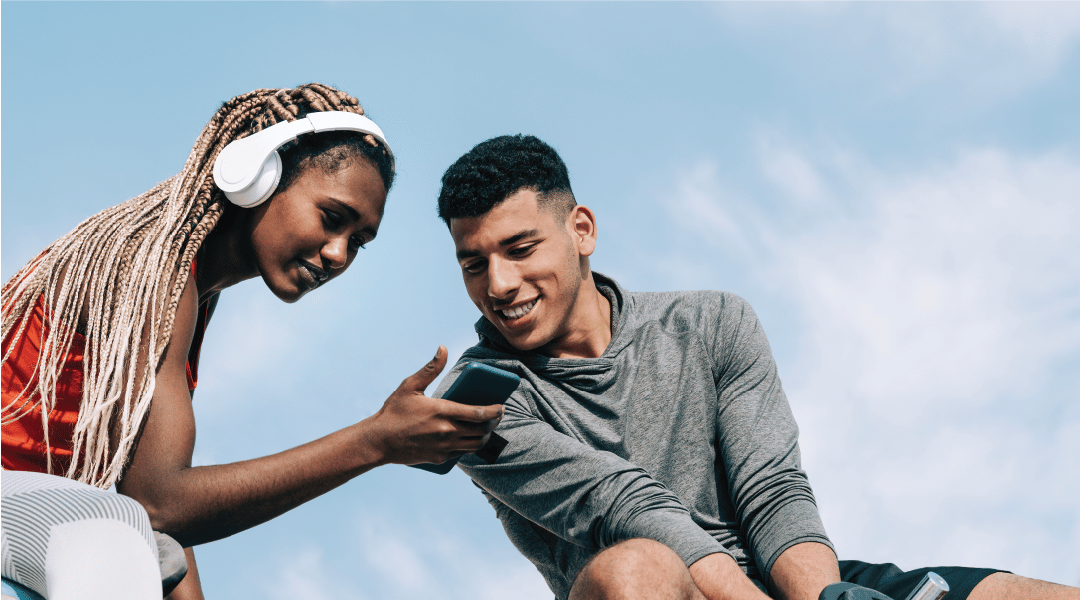 Two People Looking at Phone Outside