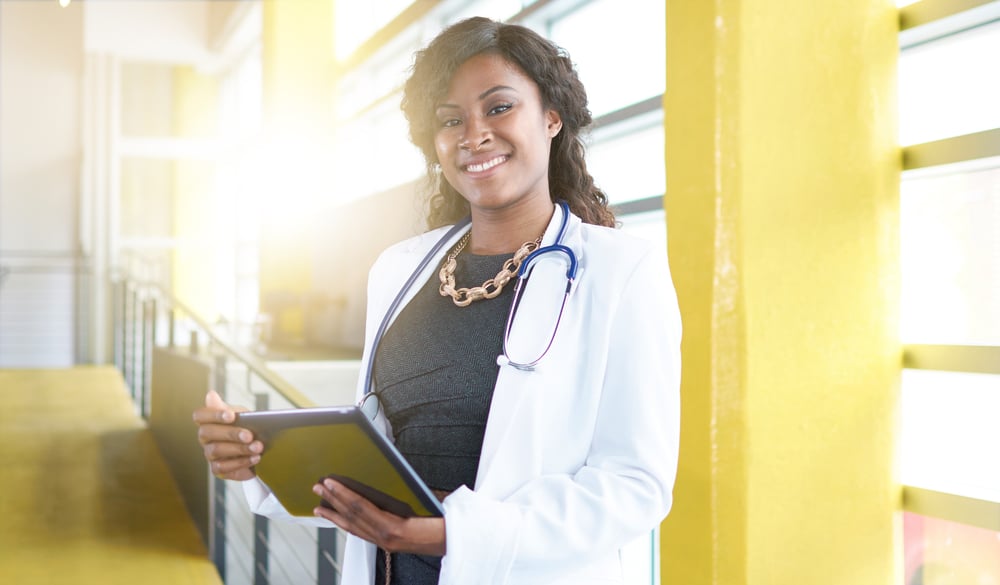 Portrait of a female doctor holding her patient chart on digital tablet in bright modern hospital-1