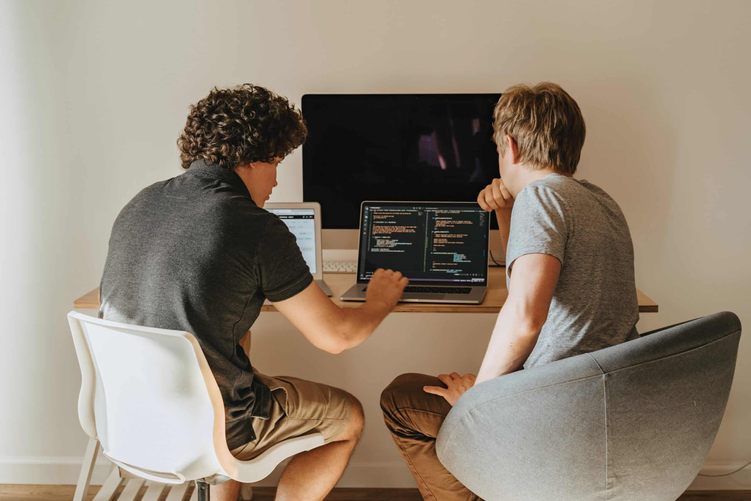 Two people sitting next to computer