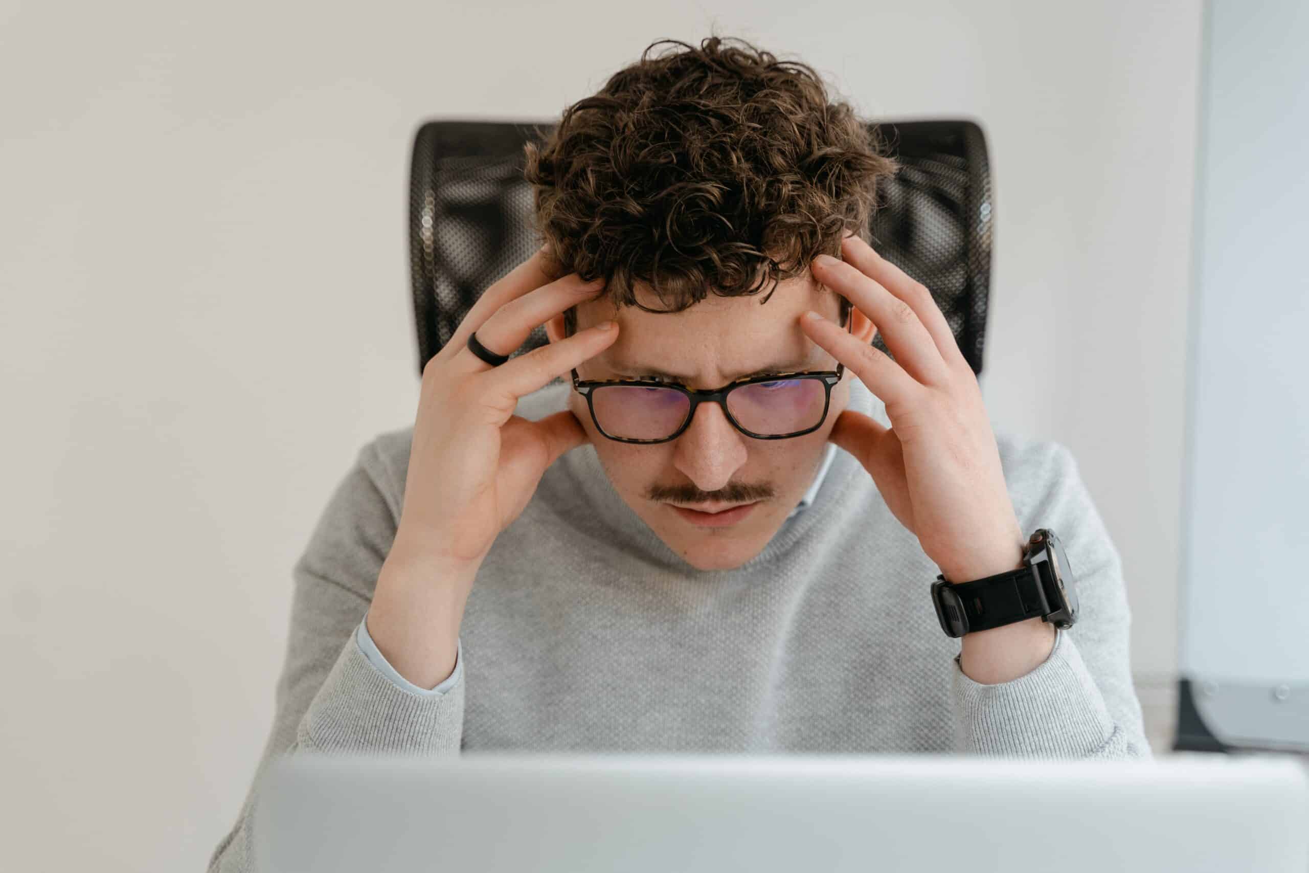 man looking down at laptop stressed