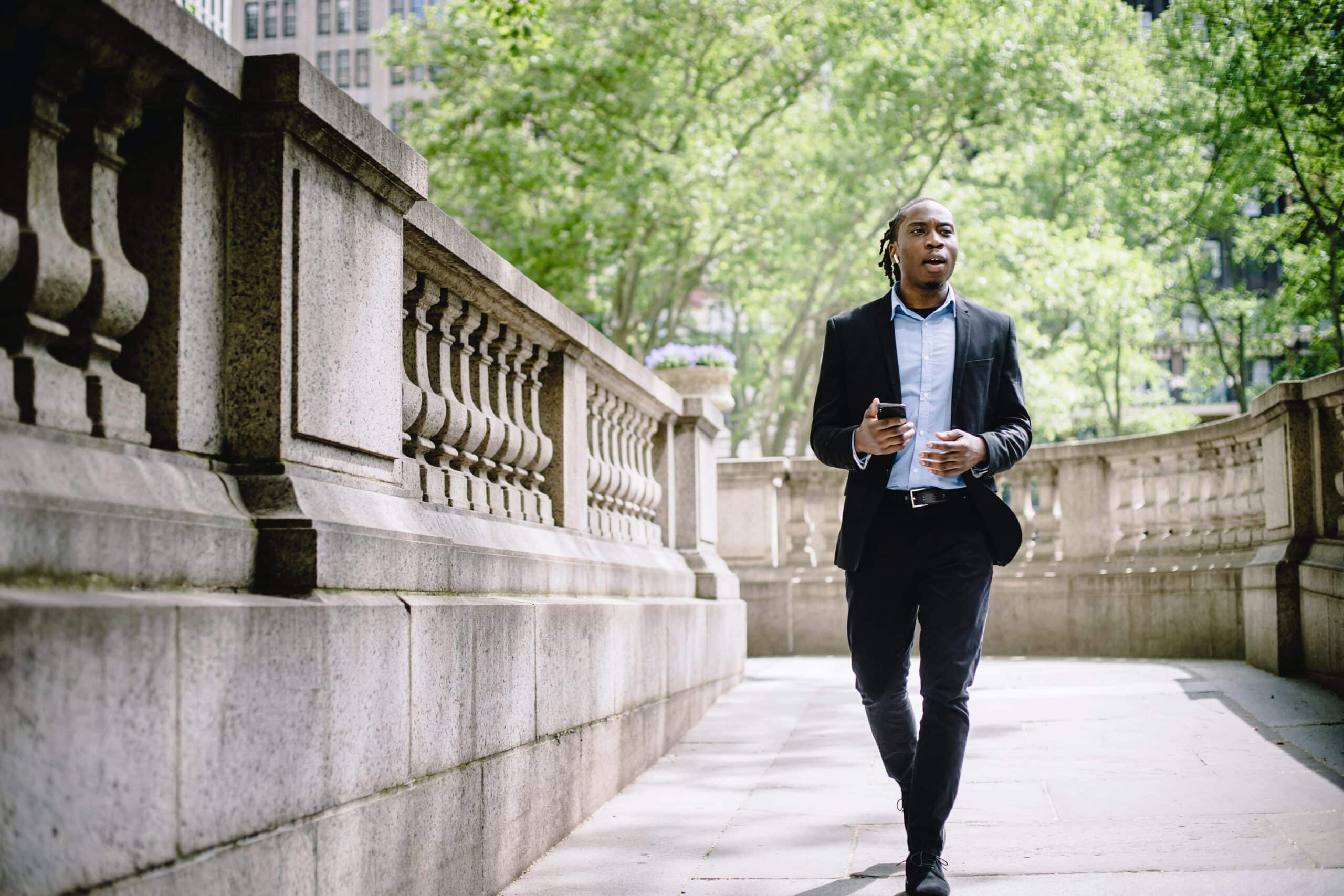 Man in suit walking in park on phone
