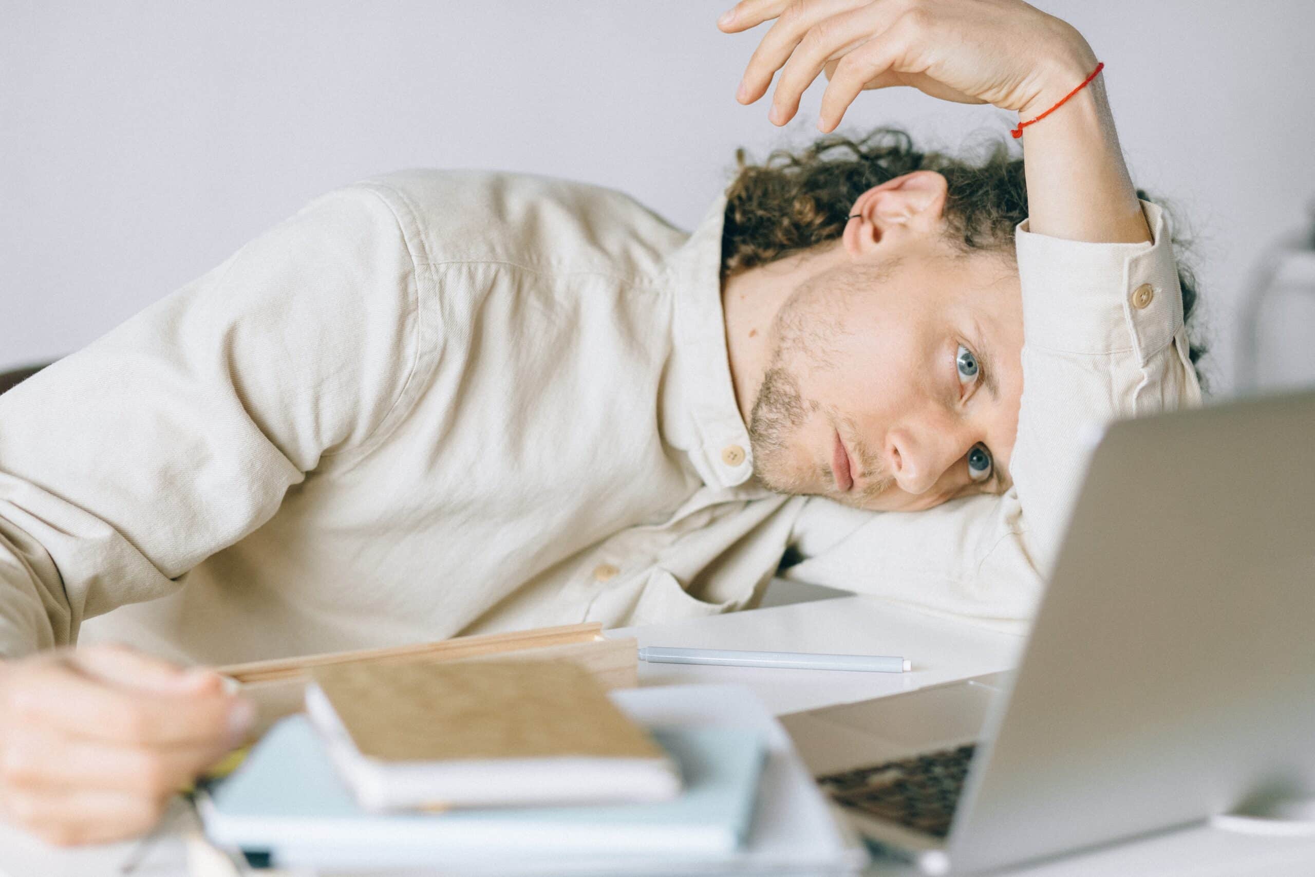 stressed man at desk in front of laptop