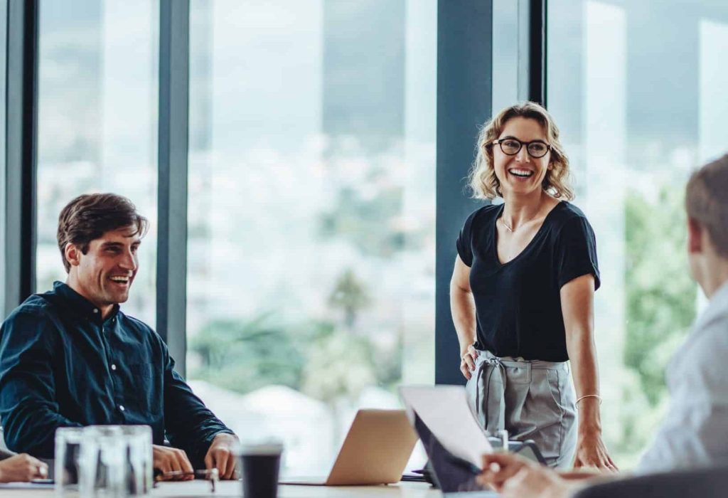 Office colleagues having casual discussion during meeting in conference room. Group of men and women sitting in conference room and smiling.