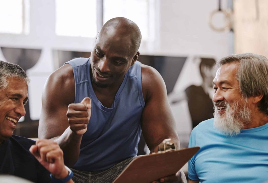 Gym, membership and personal trainer with men for sign up, planning and workout routine on blurred background. Health, checklist and coach with old people on floor for training, goals and motivation